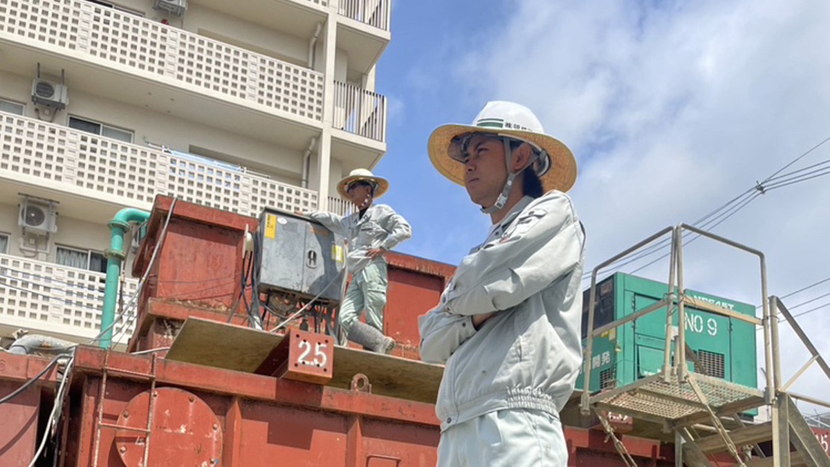 明成建設の工事現場に立つ作業服の社員